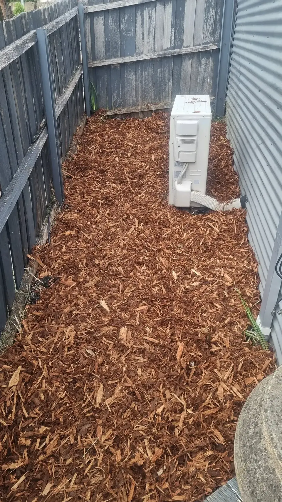 Mulched narrow side yard with cleared garden beds